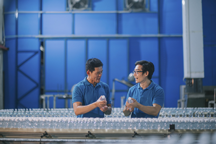mentor in discussion with colleague at manufacturing factory water bottling plant