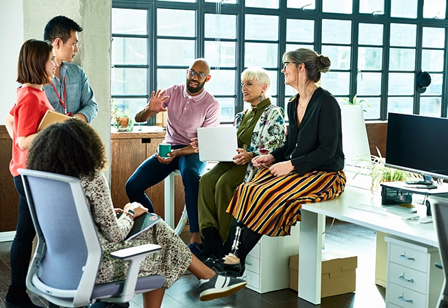 A group of people sitting at a desk and talking with each other